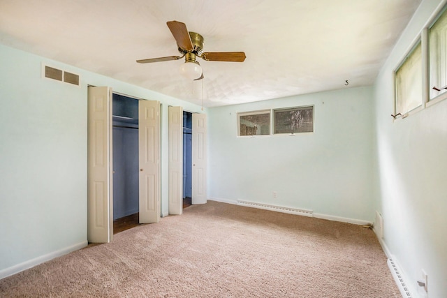 unfurnished bedroom featuring carpet, ceiling fan, a baseboard radiator, and multiple closets