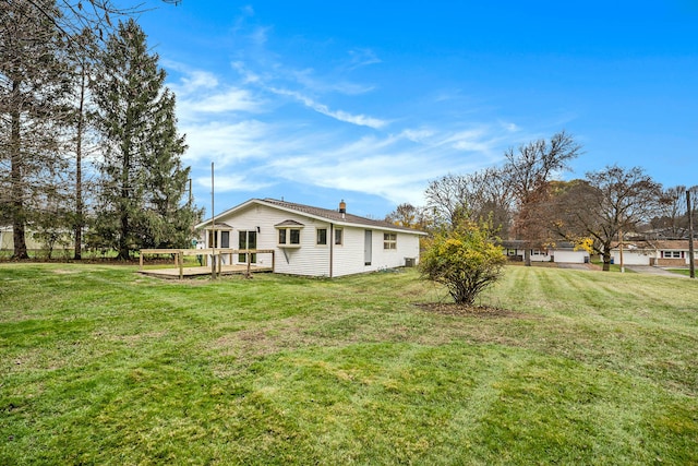 rear view of house featuring a yard and a deck