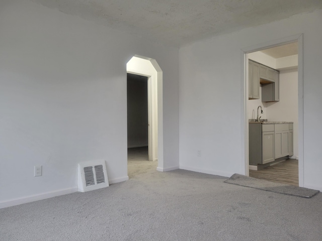 unfurnished room with carpet flooring, a textured ceiling, and sink