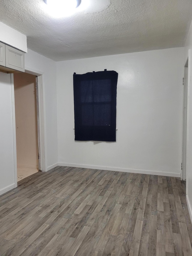 unfurnished room with a textured ceiling and light wood-type flooring