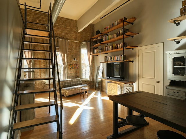 interior space with a towering ceiling, light hardwood / wood-style floors, and brick wall