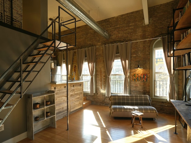 interior space with a towering ceiling, hardwood / wood-style flooring, and brick wall