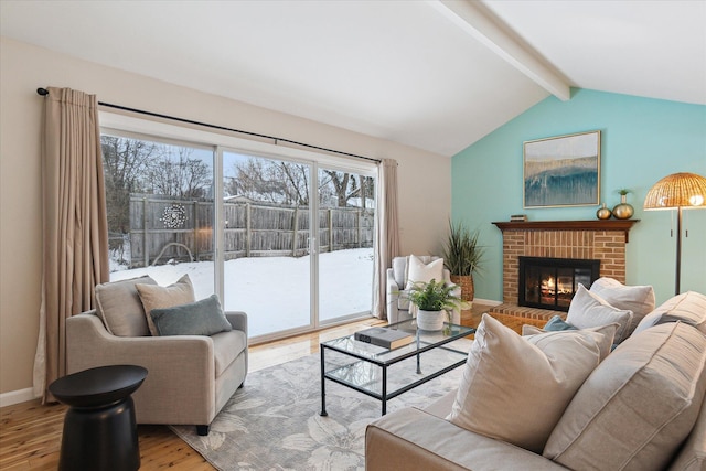 living room featuring a fireplace, light hardwood / wood-style flooring, and vaulted ceiling with beams