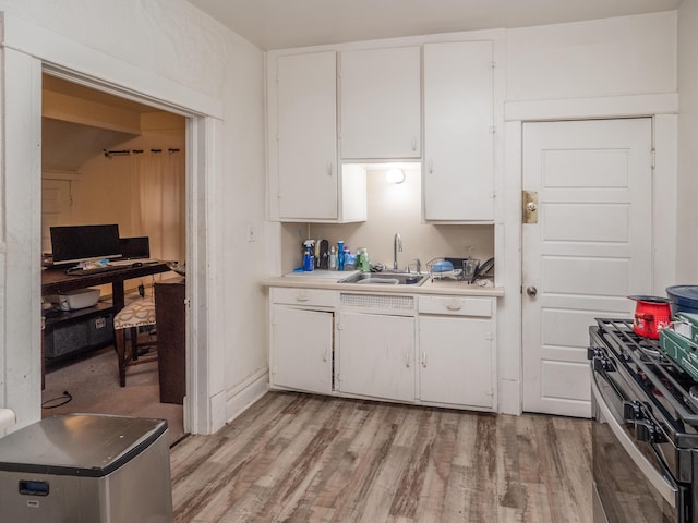 kitchen featuring white cabinets, stainless steel gas range oven, light wood-type flooring, and sink