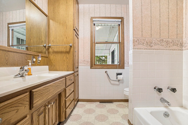 bathroom featuring vanity, toilet, and tile walls