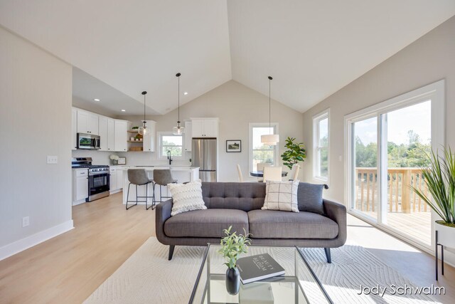 living room featuring light hardwood / wood-style floors, sink, and high vaulted ceiling