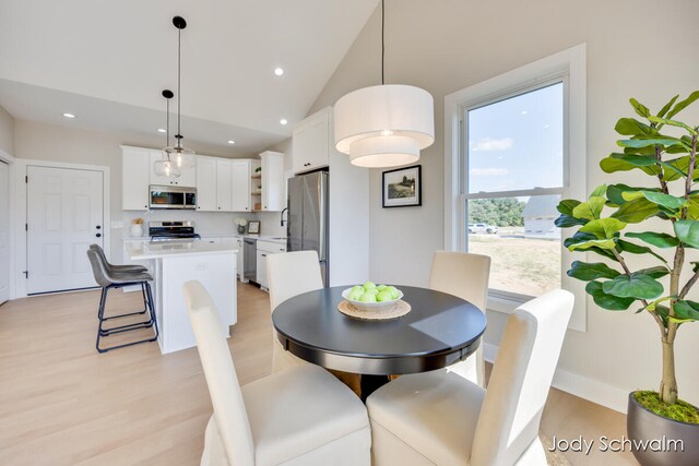 dining area featuring sink, light hardwood / wood-style floors, and lofted ceiling