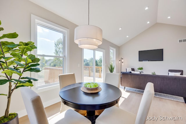 dining area with light hardwood / wood-style floors, high vaulted ceiling, and a healthy amount of sunlight