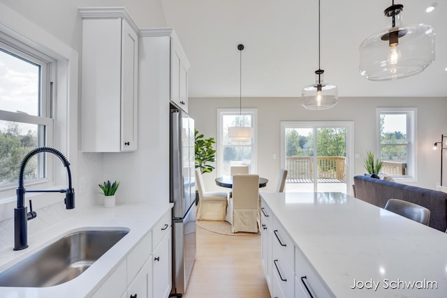 kitchen featuring white cabinets, light hardwood / wood-style floors, stainless steel refrigerator, and sink