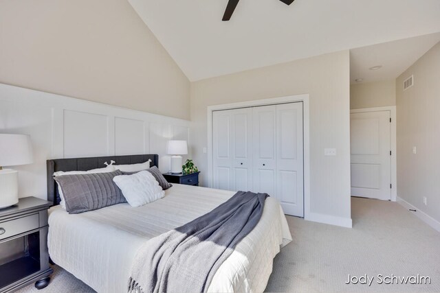 bedroom with ceiling fan, light colored carpet, lofted ceiling, and a closet