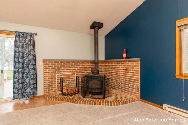 unfurnished living room featuring tile patterned floors, vaulted ceiling, a wood stove, and a baseboard heating unit