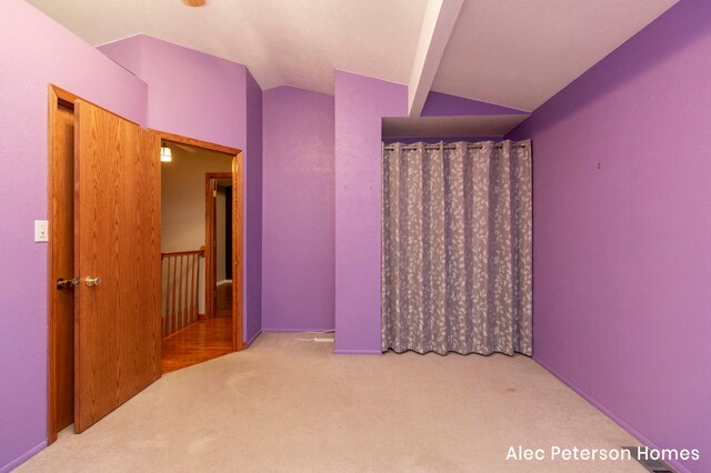 interior space featuring carpet and vaulted ceiling with beams