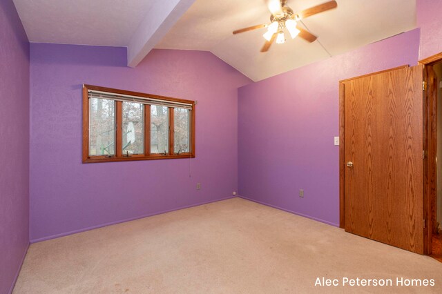 carpeted empty room featuring lofted ceiling with beams and ceiling fan