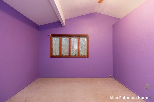 carpeted empty room featuring vaulted ceiling with beams