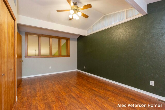 empty room with ceiling fan, lofted ceiling, and dark wood-type flooring