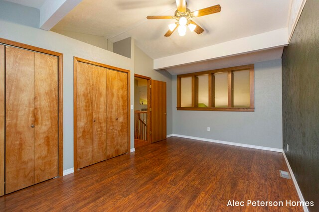 unfurnished bedroom with two closets, vaulted ceiling, ceiling fan, and dark wood-type flooring