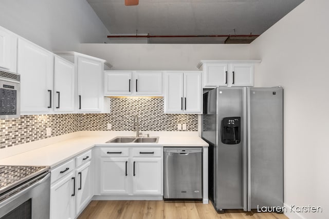 kitchen with sink, light hardwood / wood-style flooring, tasteful backsplash, white cabinetry, and stainless steel appliances