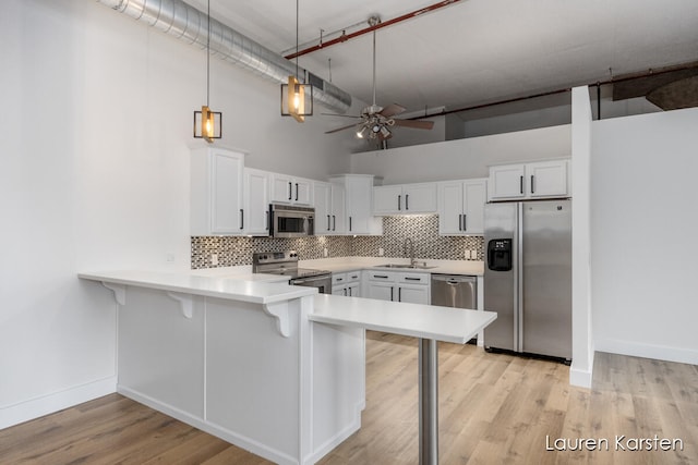 kitchen featuring white cabinets, decorative light fixtures, and stainless steel appliances