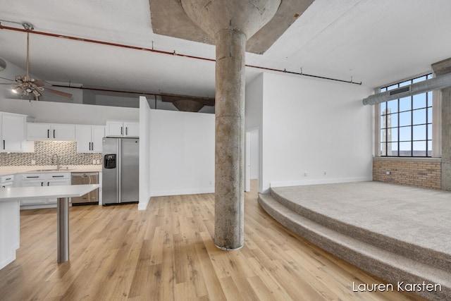 kitchen with sink, stainless steel appliances, light hardwood / wood-style flooring, brick wall, and white cabinets