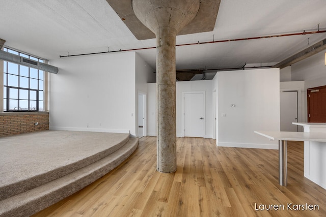 basement with hardwood / wood-style flooring and brick wall