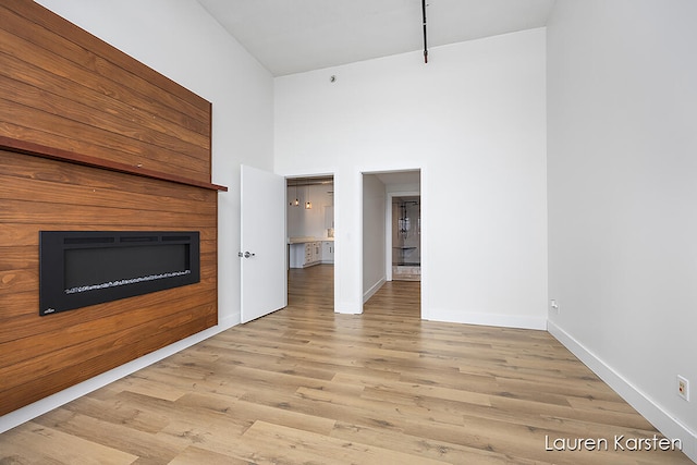 unfurnished living room featuring a high ceiling and light hardwood / wood-style flooring