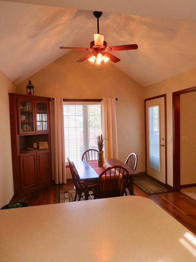 unfurnished dining area featuring ceiling fan, dark wood-type flooring, and vaulted ceiling