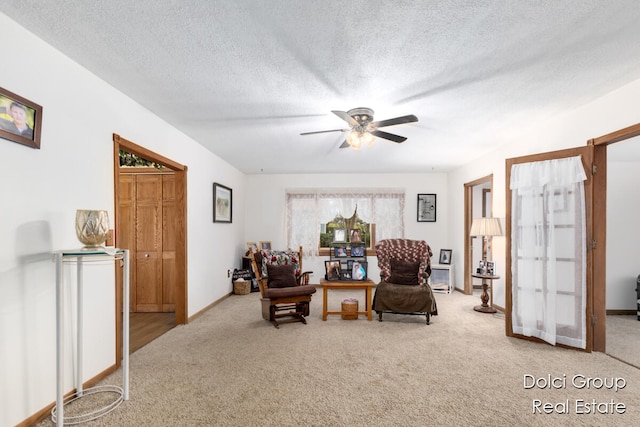 sitting room with ceiling fan, carpet, and a textured ceiling