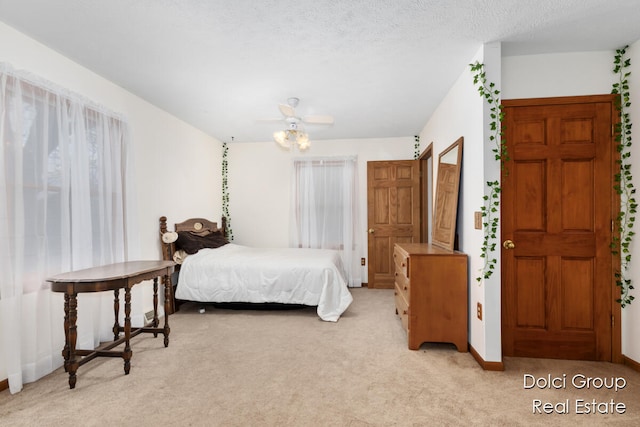 bedroom with ceiling fan, light carpet, and a textured ceiling