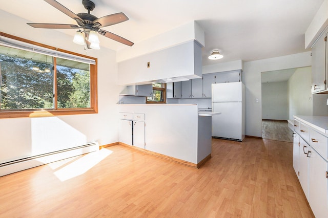 kitchen featuring baseboard heating, ceiling fan, white fridge, and light wood-type flooring