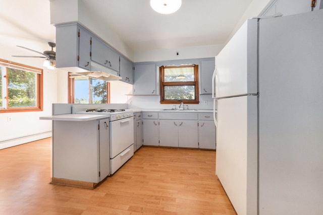 kitchen featuring kitchen peninsula, light wood-type flooring, white appliances, ceiling fan, and sink