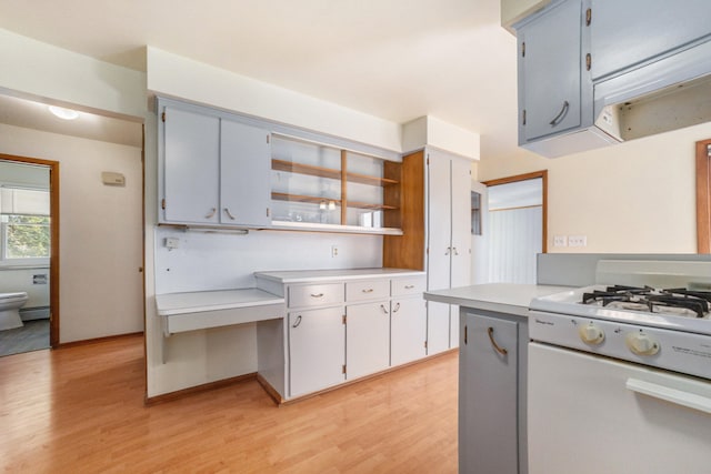 kitchen featuring white range with gas cooktop, light hardwood / wood-style flooring, gray cabinets, and exhaust hood