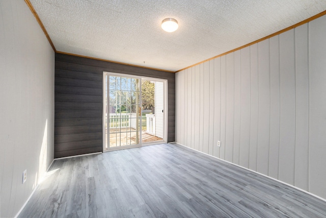 unfurnished room featuring wooden walls, hardwood / wood-style floors, and ornamental molding