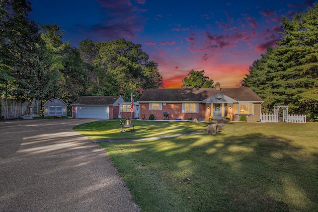 ranch-style home featuring a garage, an outdoor structure, and a lawn