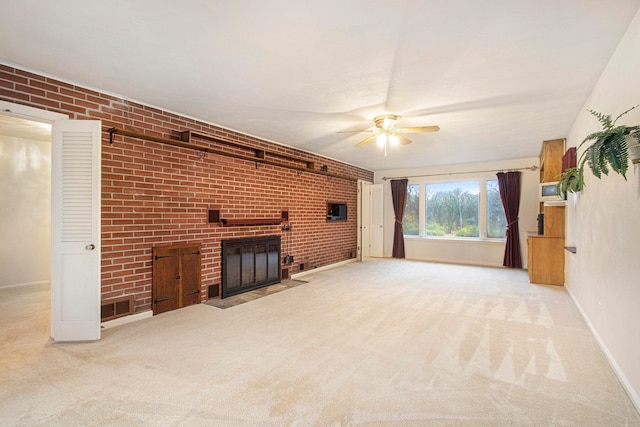 unfurnished living room featuring a fireplace, light carpet, ceiling fan, and brick wall