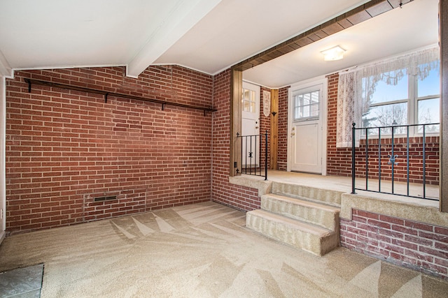 interior space with vaulted ceiling with beams and brick wall