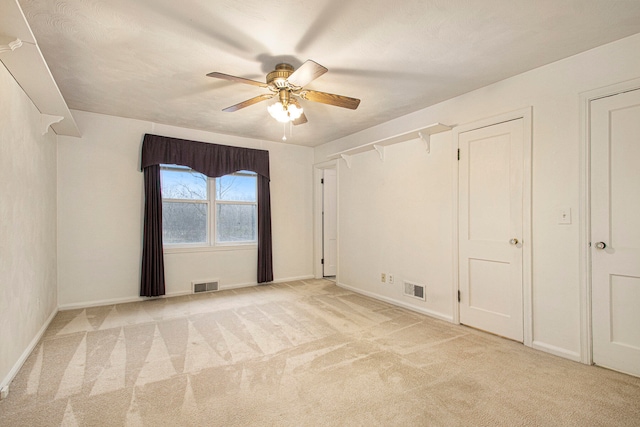 unfurnished bedroom featuring ceiling fan, light carpet, and multiple closets