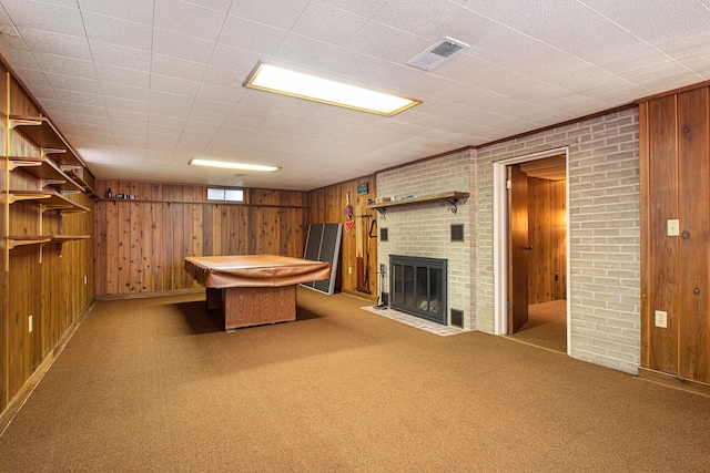 rec room featuring brick wall, billiards, wood walls, light carpet, and a fireplace