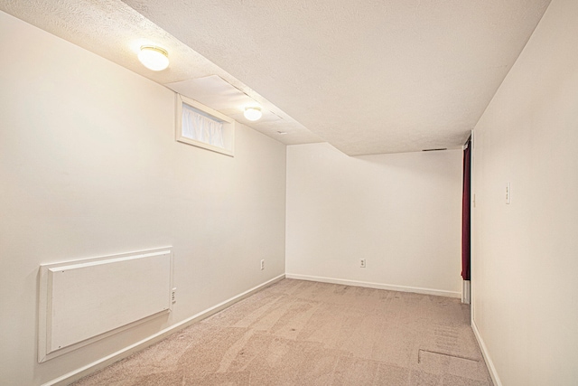 basement featuring light colored carpet and a textured ceiling