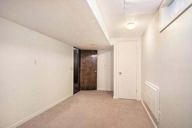 corridor with light colored carpet and a textured ceiling