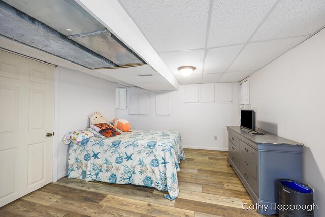 bedroom with wood-type flooring and a paneled ceiling