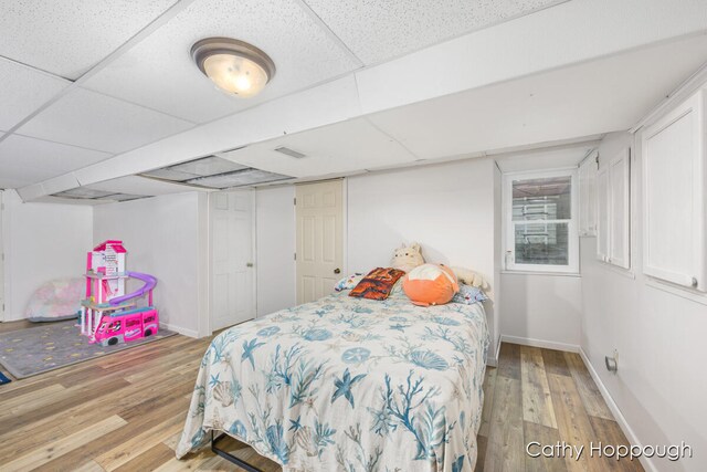 bedroom featuring a drop ceiling and wood-type flooring