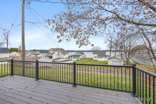 wooden deck with a garage, an outdoor structure, and a lawn