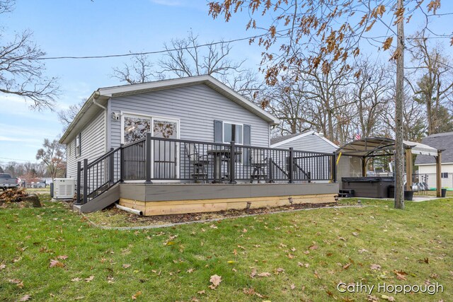 back of house with a lawn, central air condition unit, a hot tub, and a deck