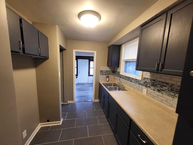 kitchen with decorative backsplash, dark tile patterned floors, and sink