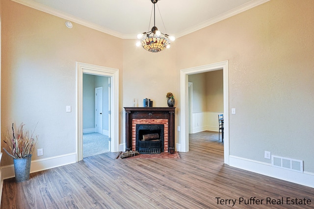 living room featuring a fireplace, hardwood / wood-style flooring, crown molding, and a notable chandelier