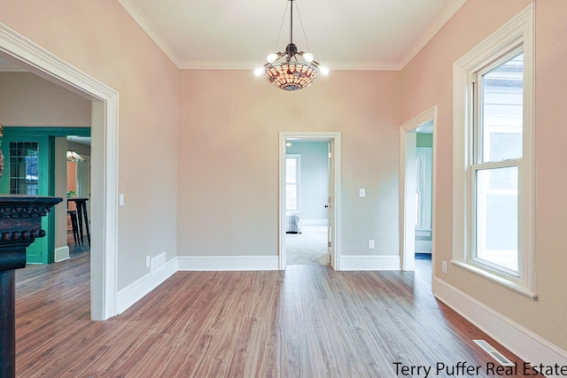 unfurnished room with a chandelier, hardwood / wood-style floors, crown molding, and a healthy amount of sunlight