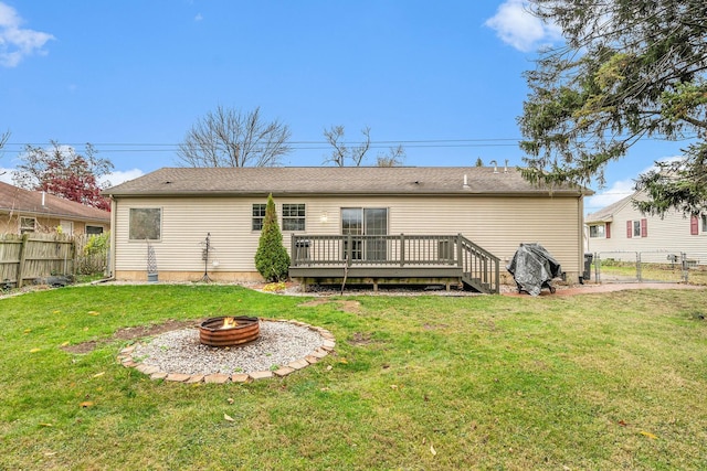 rear view of house featuring a fire pit, a lawn, and a wooden deck