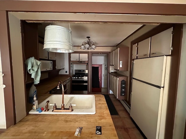 kitchen with baseboard heating, sink, white appliances, and a notable chandelier