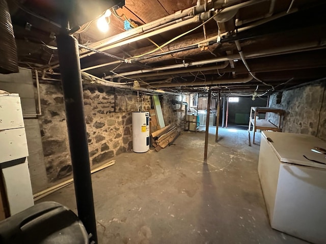 basement with washer / dryer, electric water heater, and white refrigerator