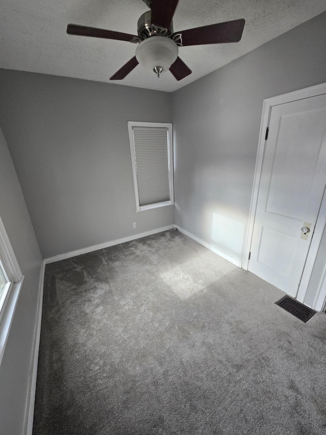 carpeted empty room featuring ceiling fan and a textured ceiling